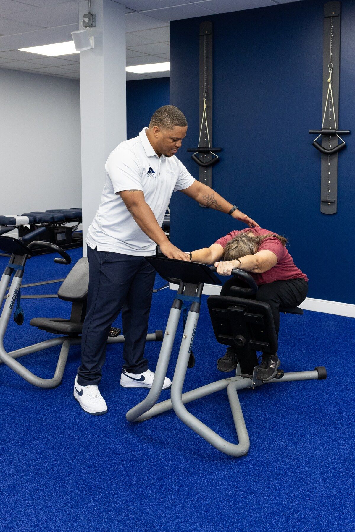 Charles Dennis supports a patient's upper back during a stretch on the stretch trainer