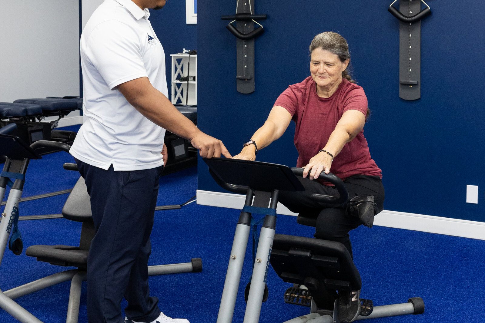 Physical therapist coaches a patient kneeling on a stretch trainer