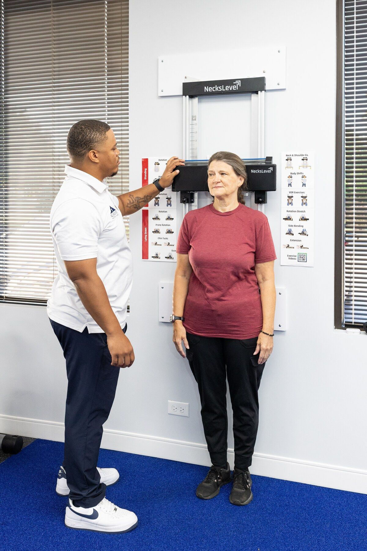Charles Dennis adjusts the headrest of a wall-mounted posture unit behind a standing patient