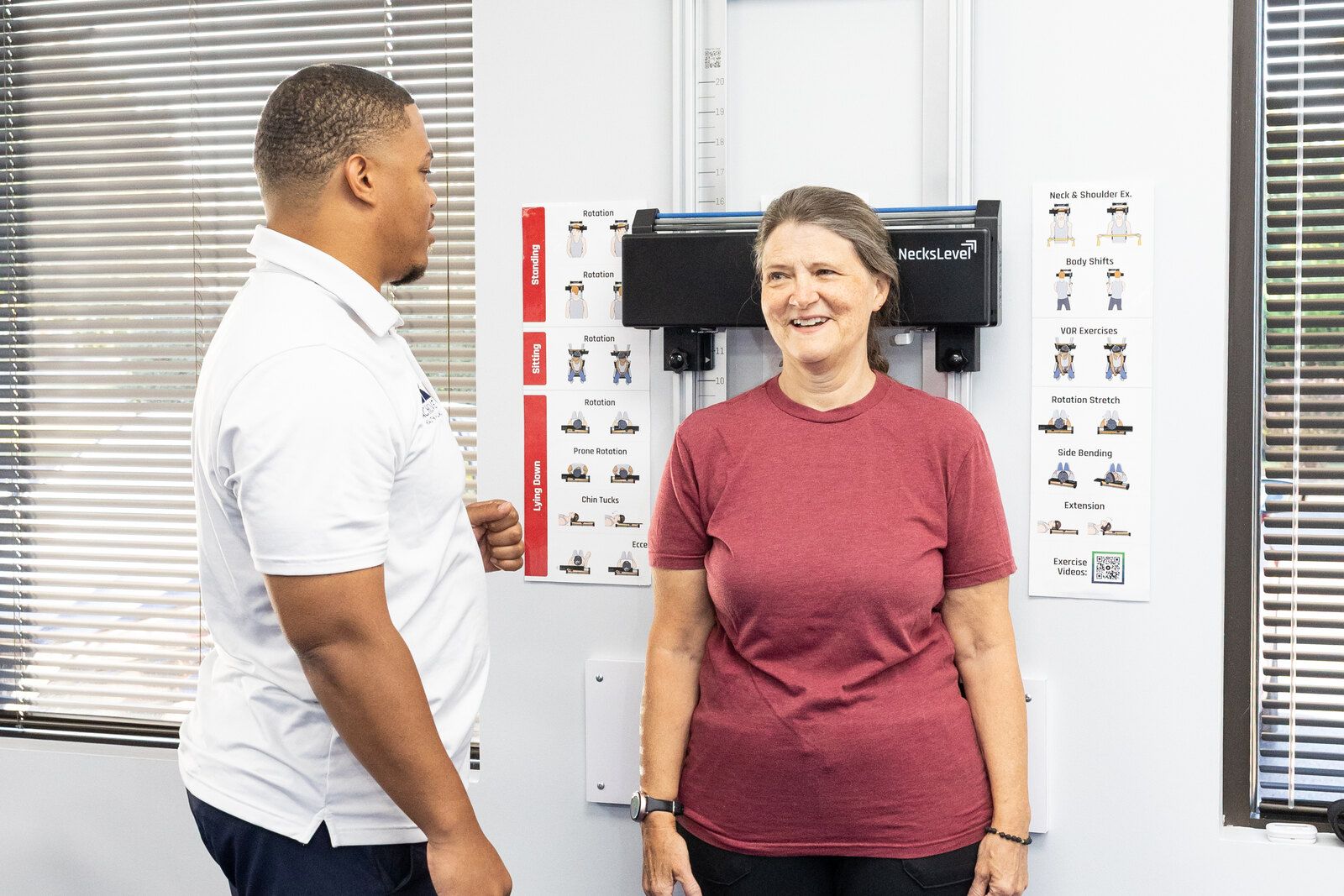 Patient stands relaxed against the wall posture unit talking with her therapist