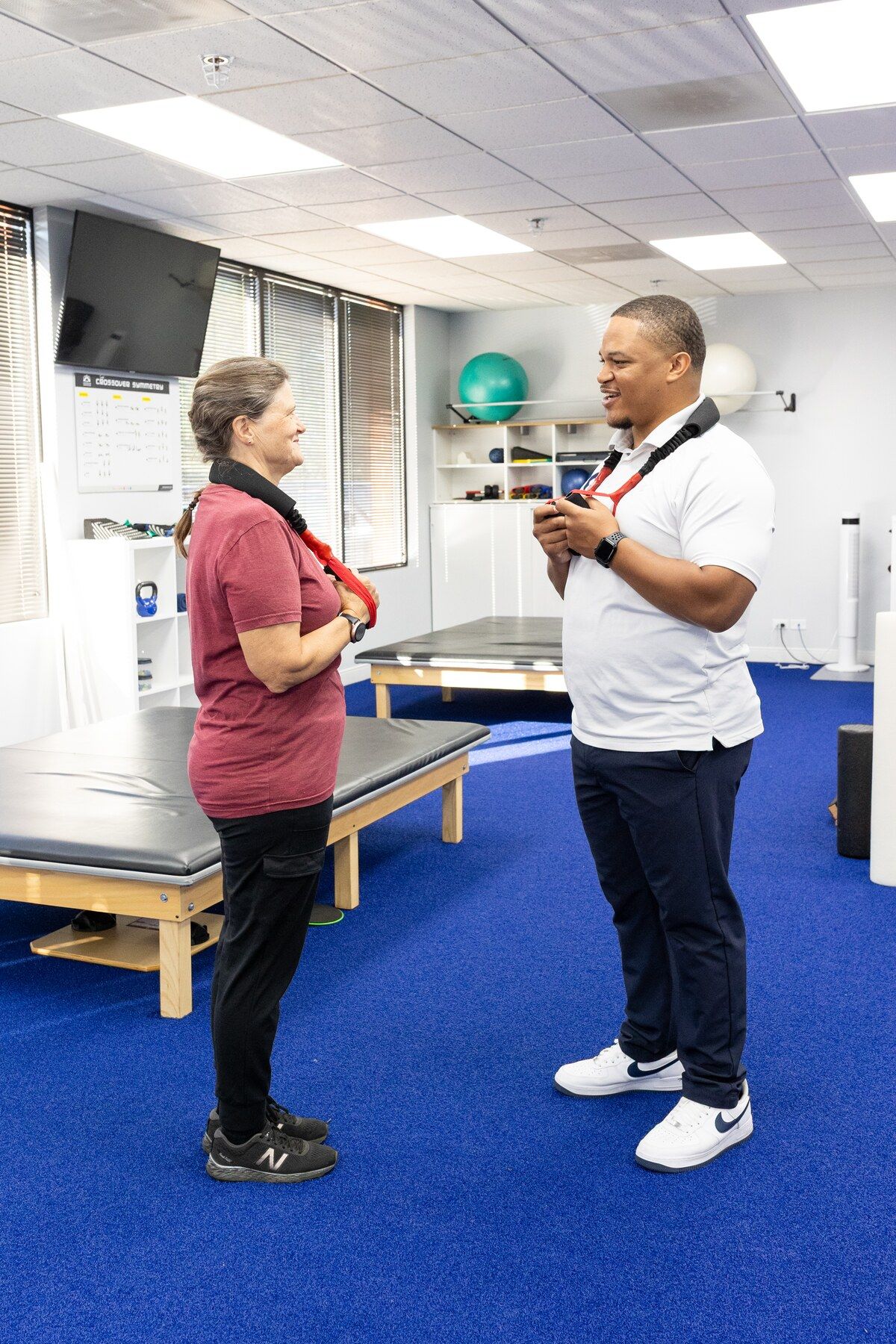 Charles Dennis and a patient stand facing each other wearing padded neck traction bands