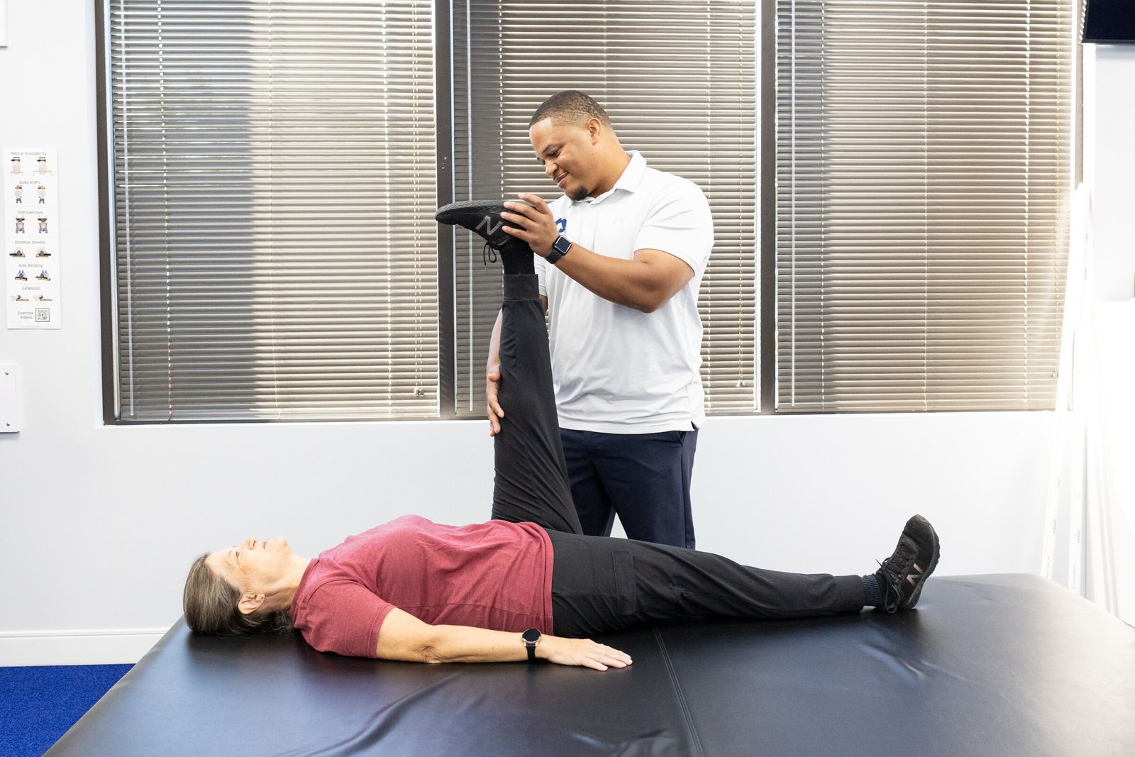 Charles Dennis raises a patient's straight leg while she lies on a mat table