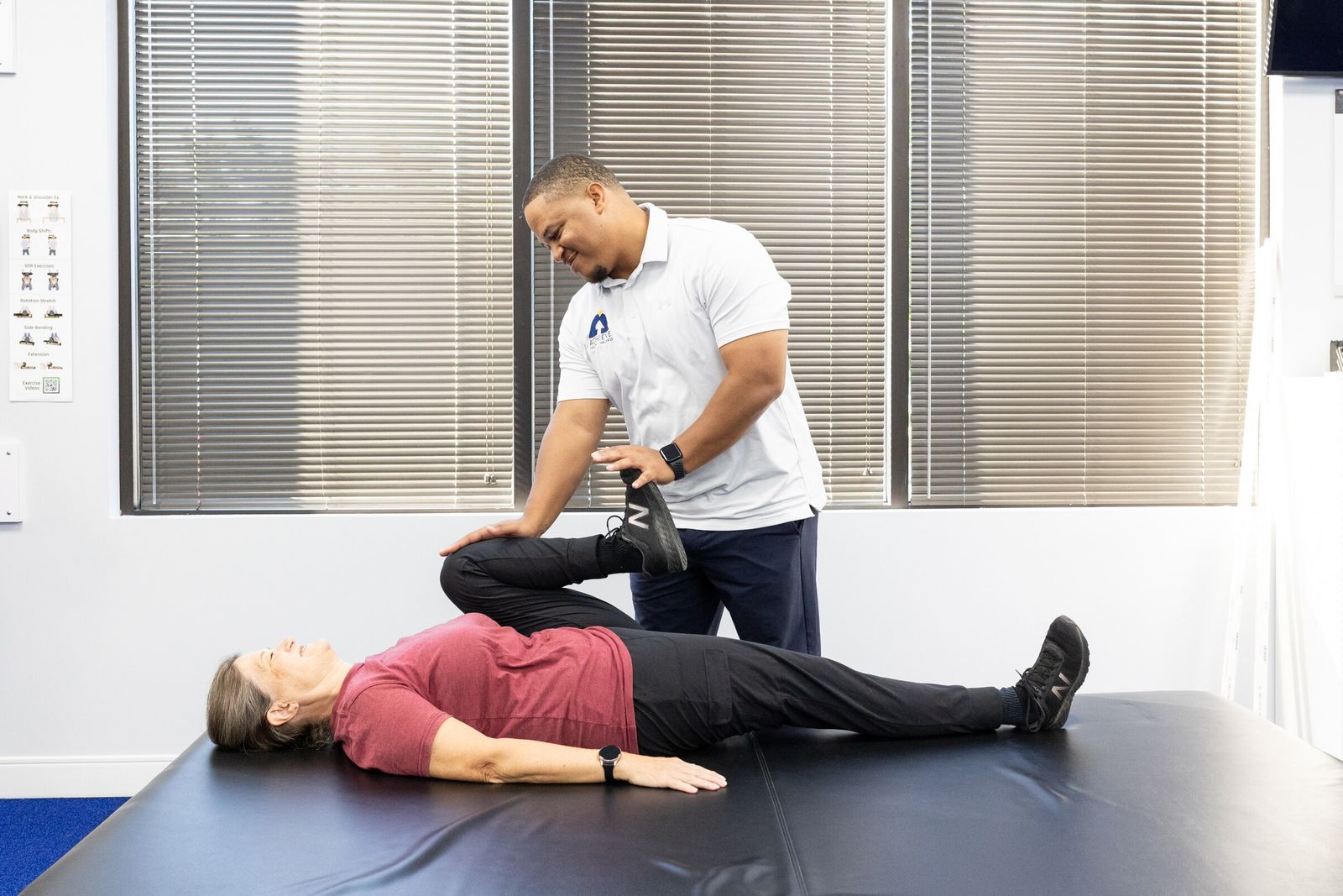 Charles Dennis bends a patient's knee toward her chest on a mat table
