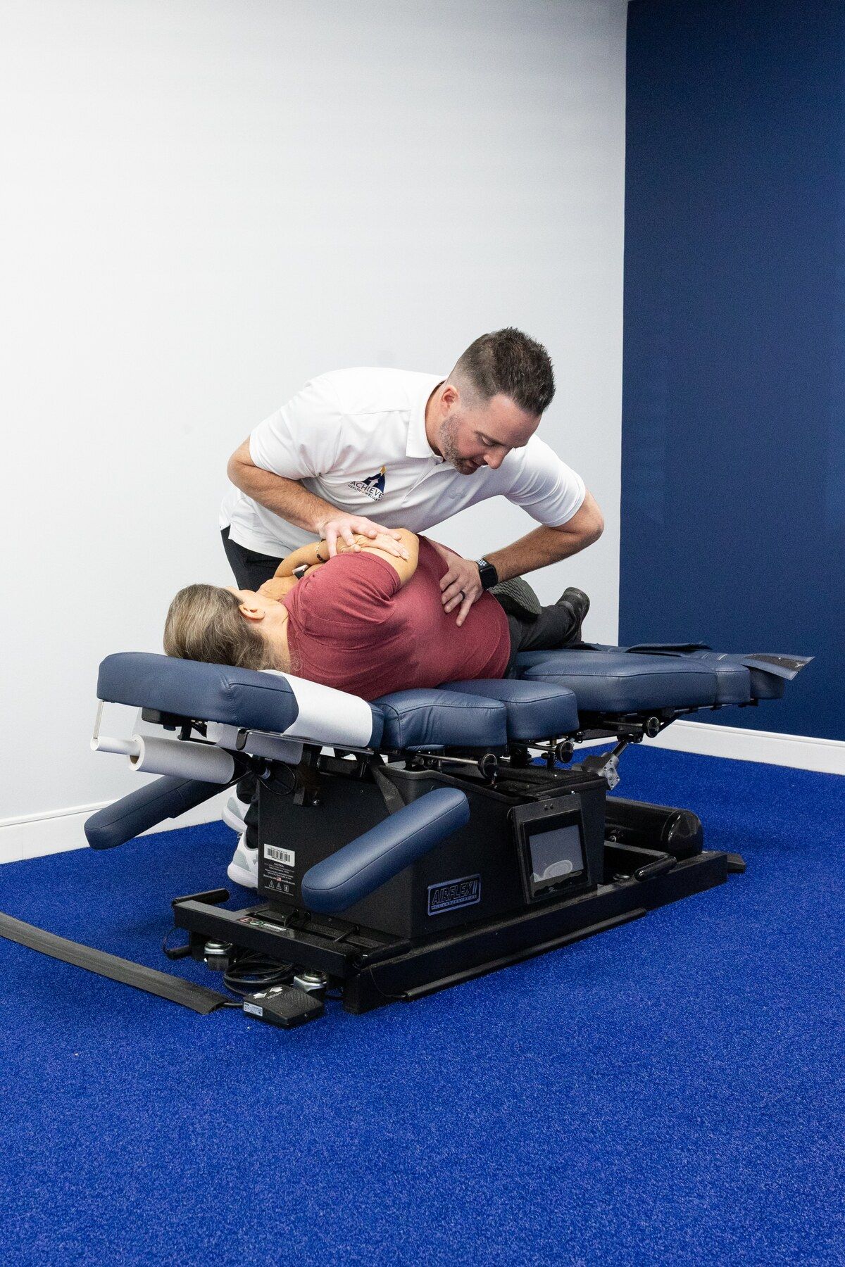 Chiropractor treats a patient lying on her side on a drop table