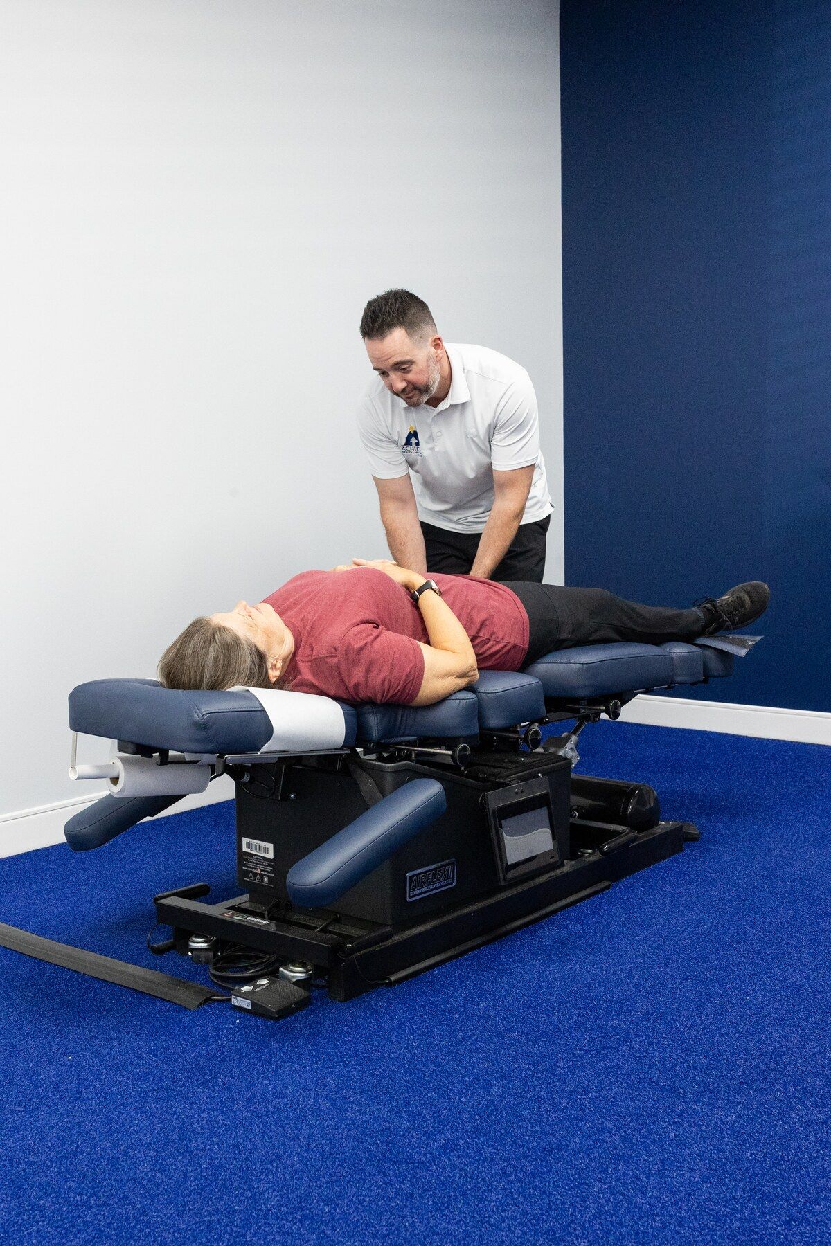 Chiropractor smiles at a patient while assessing her pelvis on the table