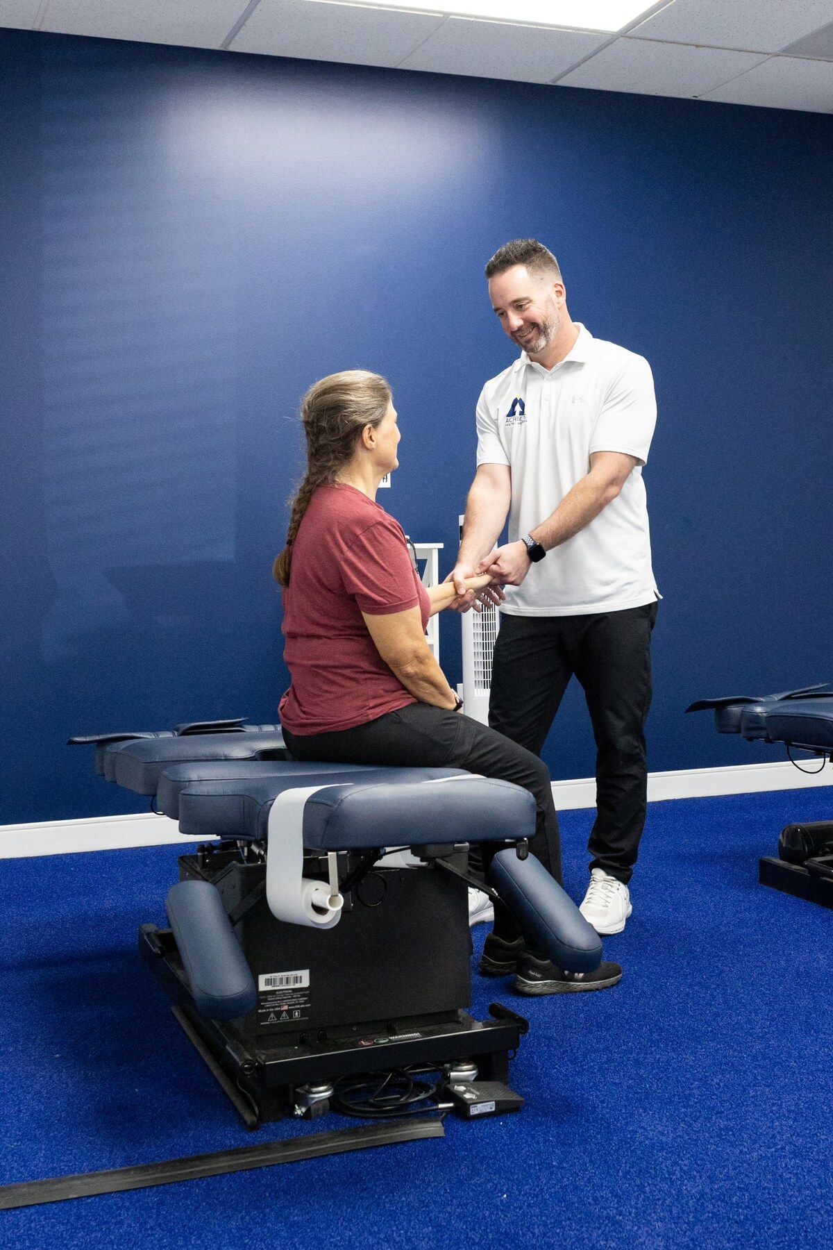 Patient seated on a treatment table as the chiropractor examines her wrist