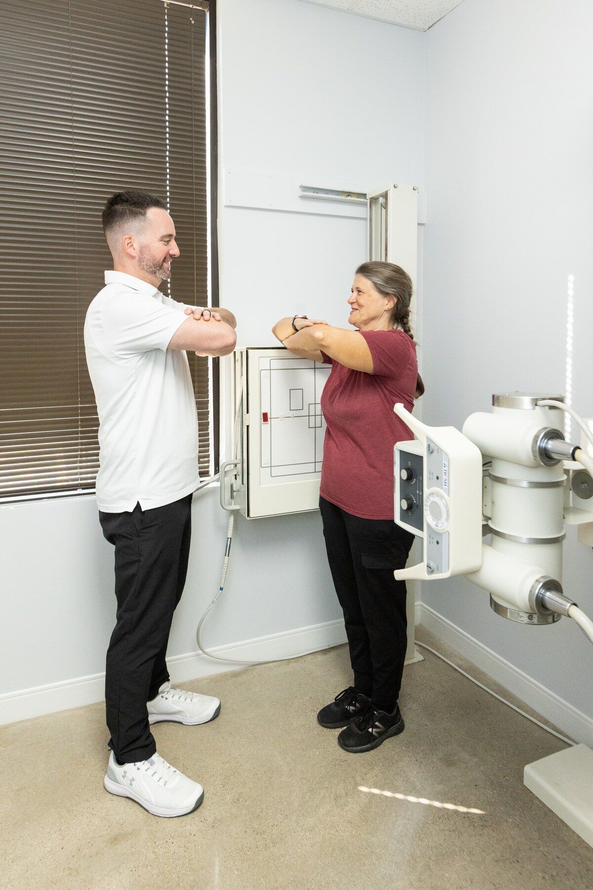 Chiropractor positions a patient against the wall x-ray unit