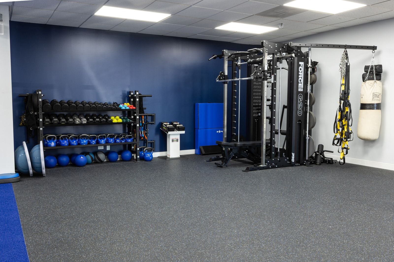 Gym corner with dumbbell rack, kettlebells, cable rig and heavy bag