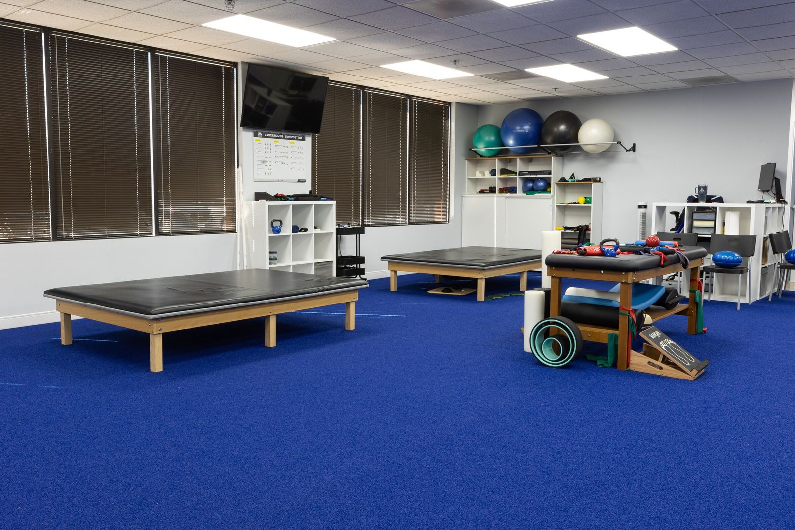 Physical therapy room with mat tables, a treatment table and foam rollers